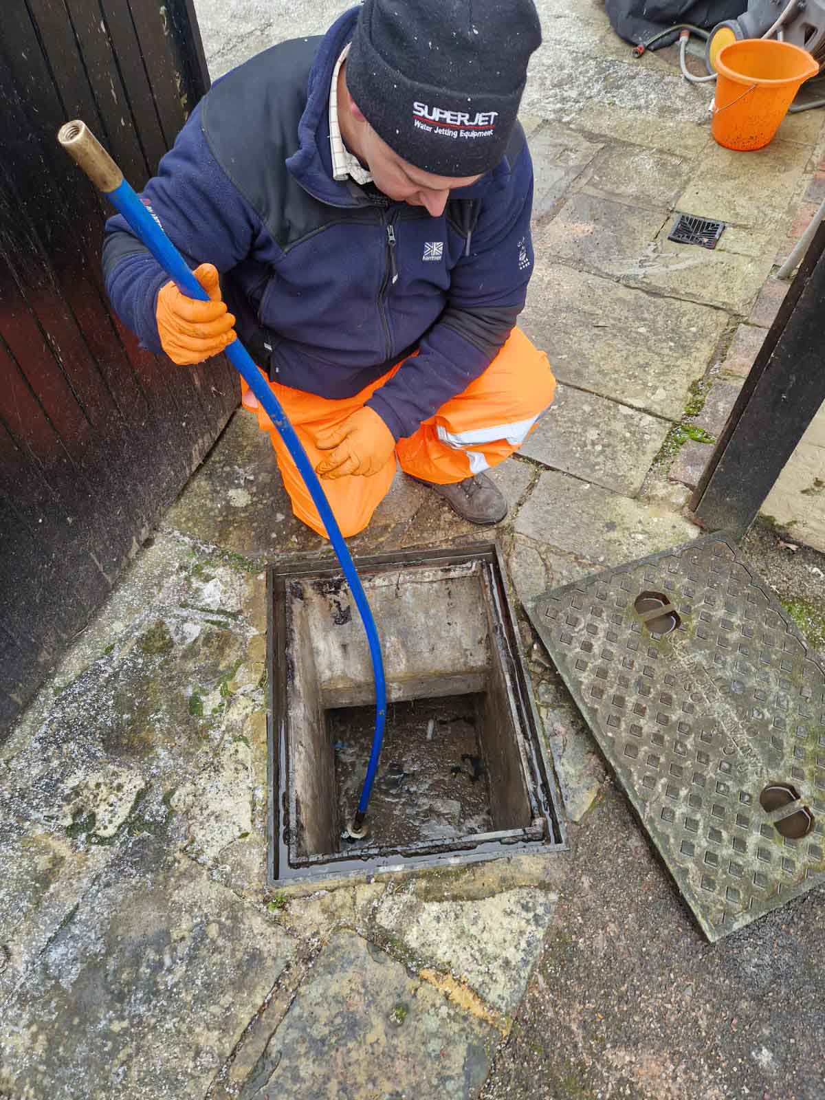 Declan from Drain Ace clearing a blocked drain in Epsom using drain rods on a cold winter morning