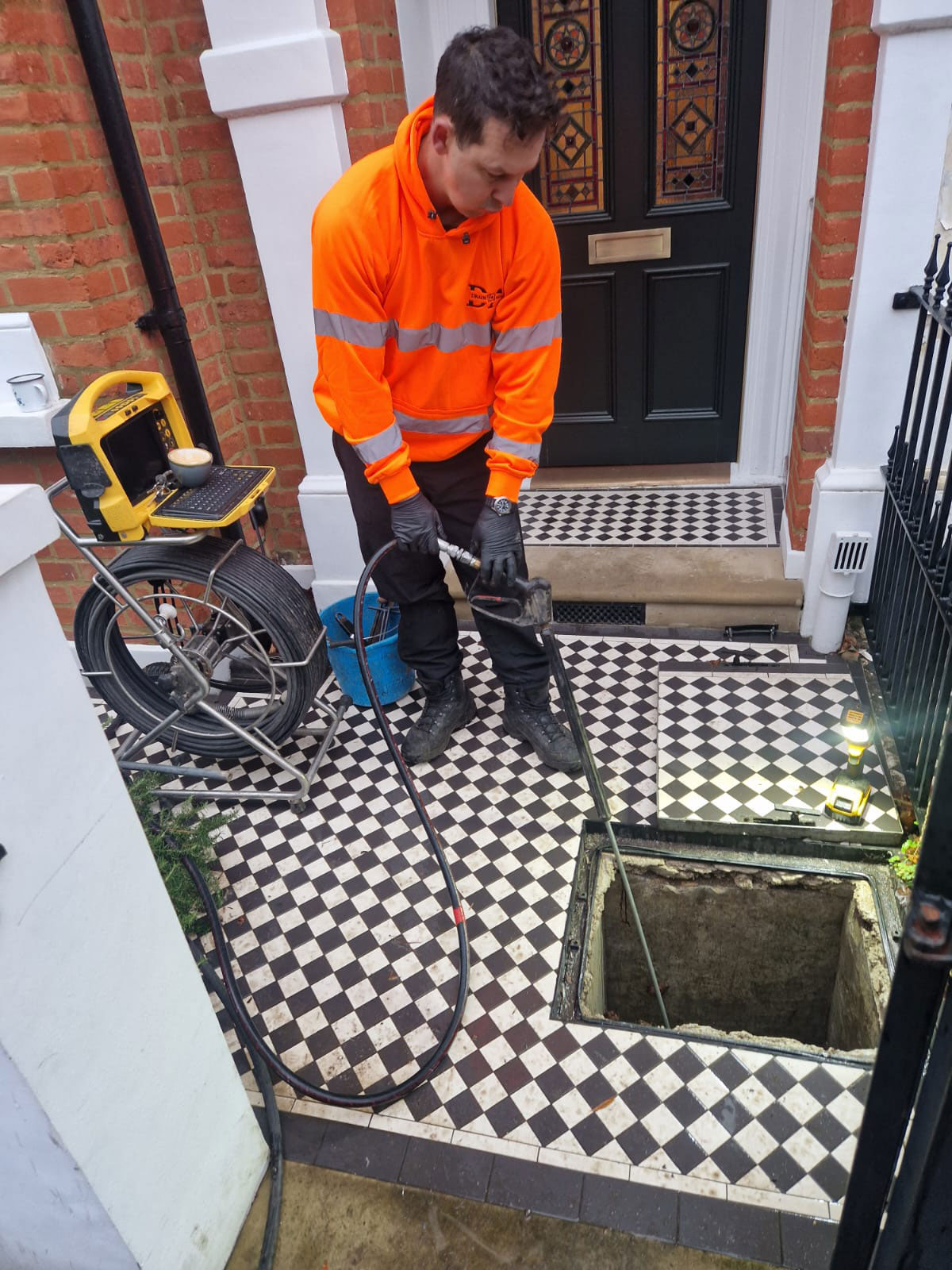 Declan from Drain Ace using high pressure drain jetting to clear a deep drain blockage in Clapham outside a Victorian property